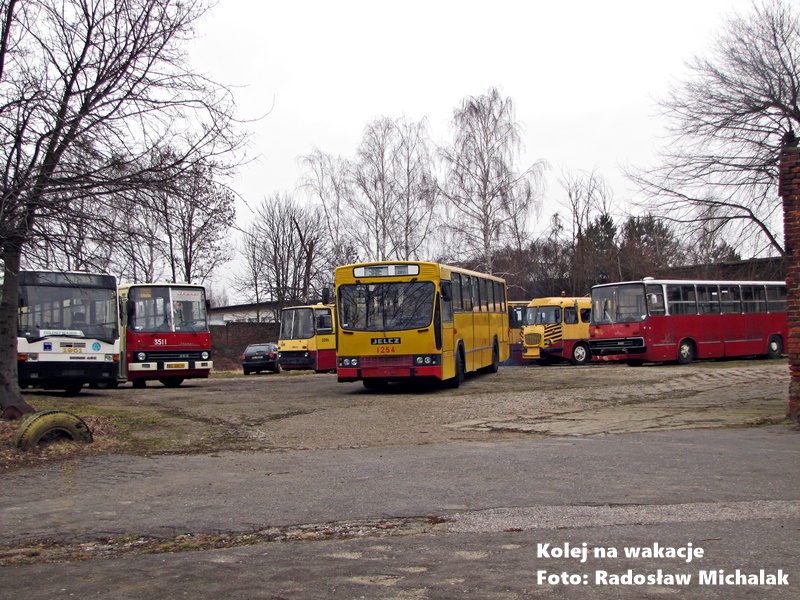 Ekspozycja zabytkowych autobusów (m.in. marki Ikarus lub Jelcz) na otwartej przestrzeni zajezdni Brus. Pojazdy stoją na tle historycznych zabudowań remizy, prezentując historię komunikacji autobusowej.