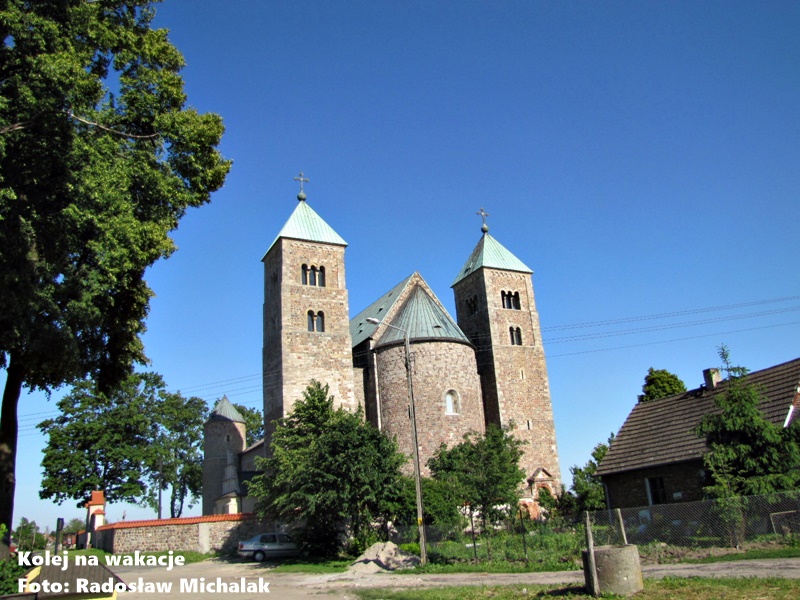 Archikolegiata w Tumie pod Łęczycą – monumentalny, romański kościół z dwiema wieżami z XII wieku, widok z zewnątrz na kamienne mury.