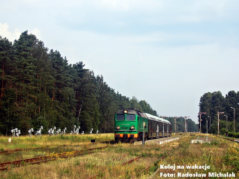 Historyczne ujęcie ze stacji Lipowa Tucholska z lipca 2010 roku. Na torach stoi ciężka spalinowa lokomotywa ST44-949 (popularny „Gagarin”) w zielonym malowaniu, do której podpięty jest skład oliwkowych wagonów piętrowych typu Bipa. W tle widać panoramę stacji i gęstą ścianę Borów Tucholskich.