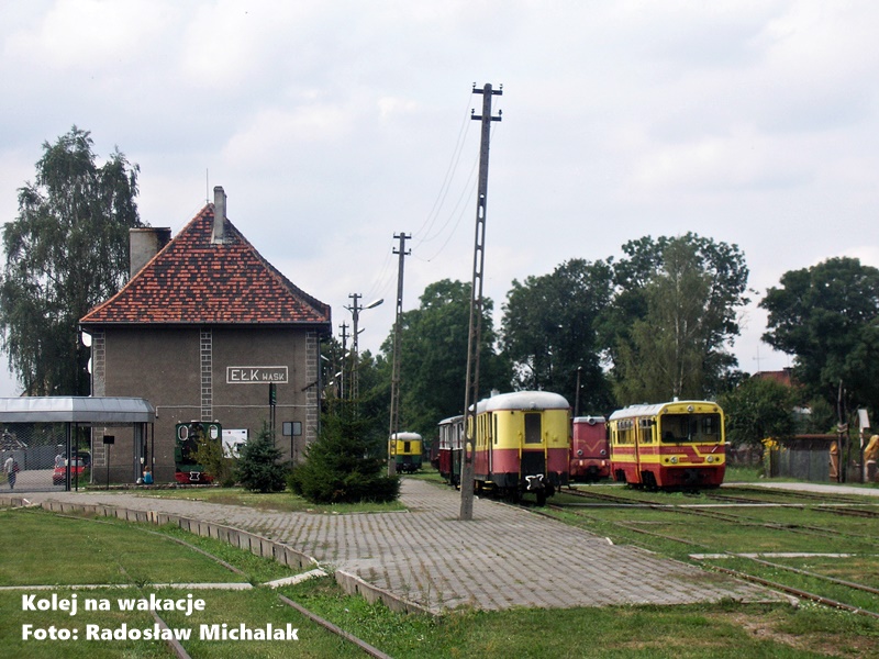 Panorama stacji Ełk Wąskotorowy z widokiem na tory i zabytkową infrastrukturę kolejową.