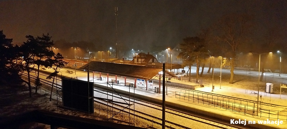 Nocne zdjęcie stacji kolejowej w Helu w czasie śnieżycy, z oświetlonym peronem zasypanym śniegiem