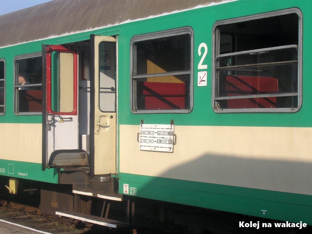 Fragment wagonu 120A (Bonanza) w klasycznym kremowo-zielonym malowaniu na peronie w Chojnicach. Wieczorne ujęcie z otwartymi drzwiami i uchylonym oknem,