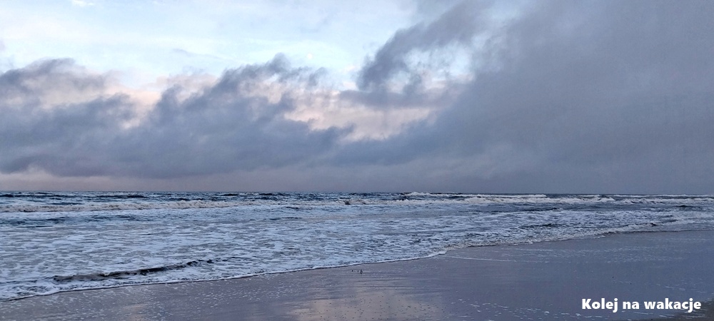 Szeroki kadr przedstawiający brzeg morza w Jastarni zimą. Wieczorne światło, ciemna woda Bałtyku i pusta plaża pokryta chłodnym, grudniowym cieniem.