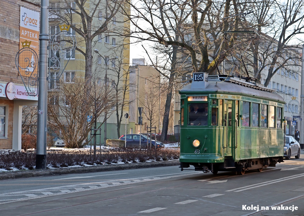 Zabytkowy tramwaj Lilpop II jedzie środkiem ulicy w Pabianicach. Wagon oznaczony jest numerem linii 125. W tle widać miejską zabudowę, witryny sklepowe i ośnieżone chodniki, co podkreśla zimową aurę wydarzenia.
