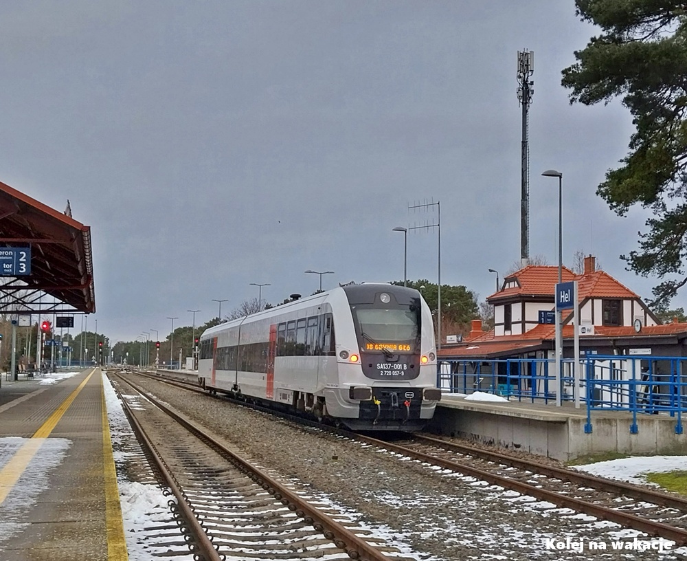 Spalinowy zespół trakcyjny SA137-001 stoi na ośnieżonym peronie stacji Hel w zimowej scenerii.