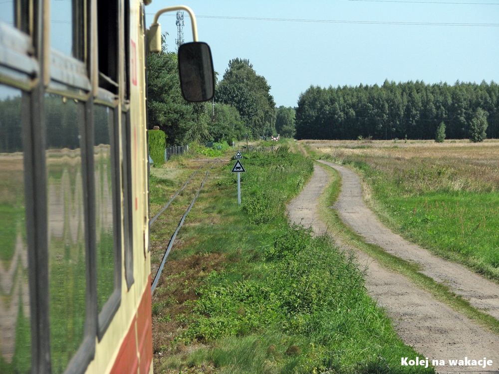 Widok ze schodów wagonu motorowego MBxd2 na tor Żuławskiej Kolei Dojazdowej w kierunku stacji Prawy Brzeg Wisły.