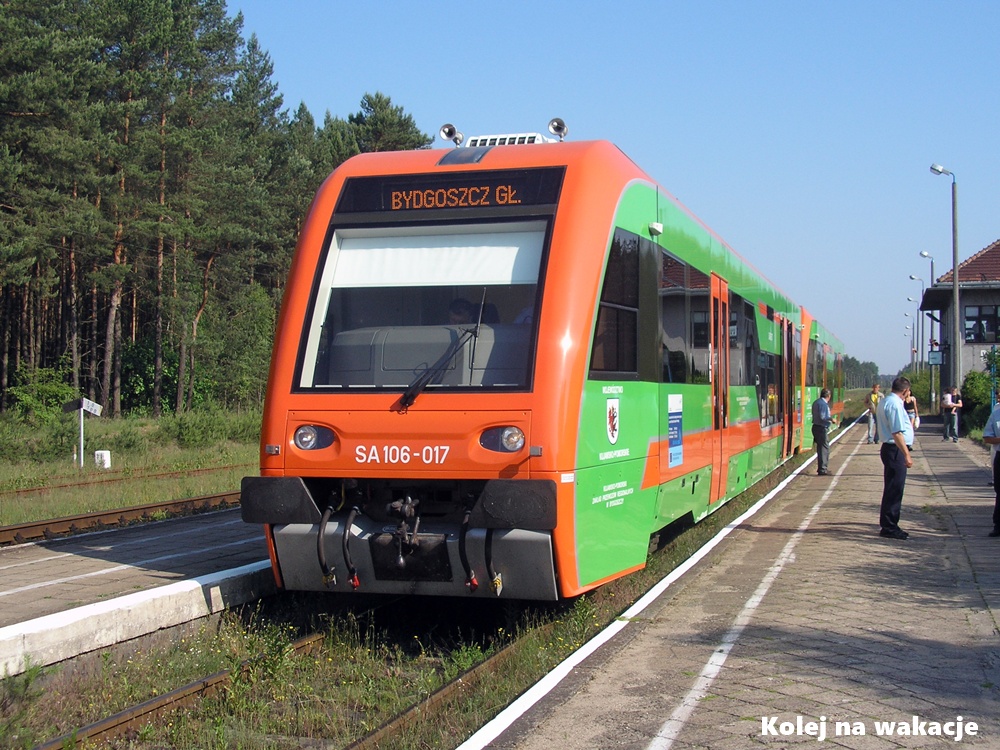 Archiwalne zdjęcie ze stacji Wierzchucin (czerwiec 2007 r.). Przy peronie stoi zielono-pomarańczowy autobus szynowy SA106-017 w barwach województwa kujawsko-pomorskiego, pociąg relacji do Bydgoszczy.