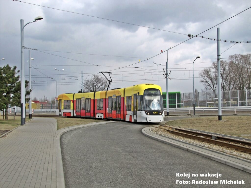 Niskopodłogowy tramwaj Bombardier Cityrunner nr 1204 wjeżdża na pętlę Chocianowice-IKEA w Łodzi. Wagon linii 11 pokonuje łuk torowiska w pochmurny dzień.