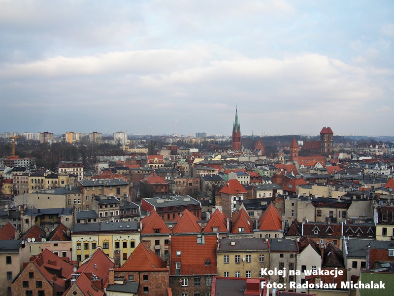 Panorama zabytkowego centrum Torunia z lotu ptaka, widoczne czerwone dachy gotyckich budowli.