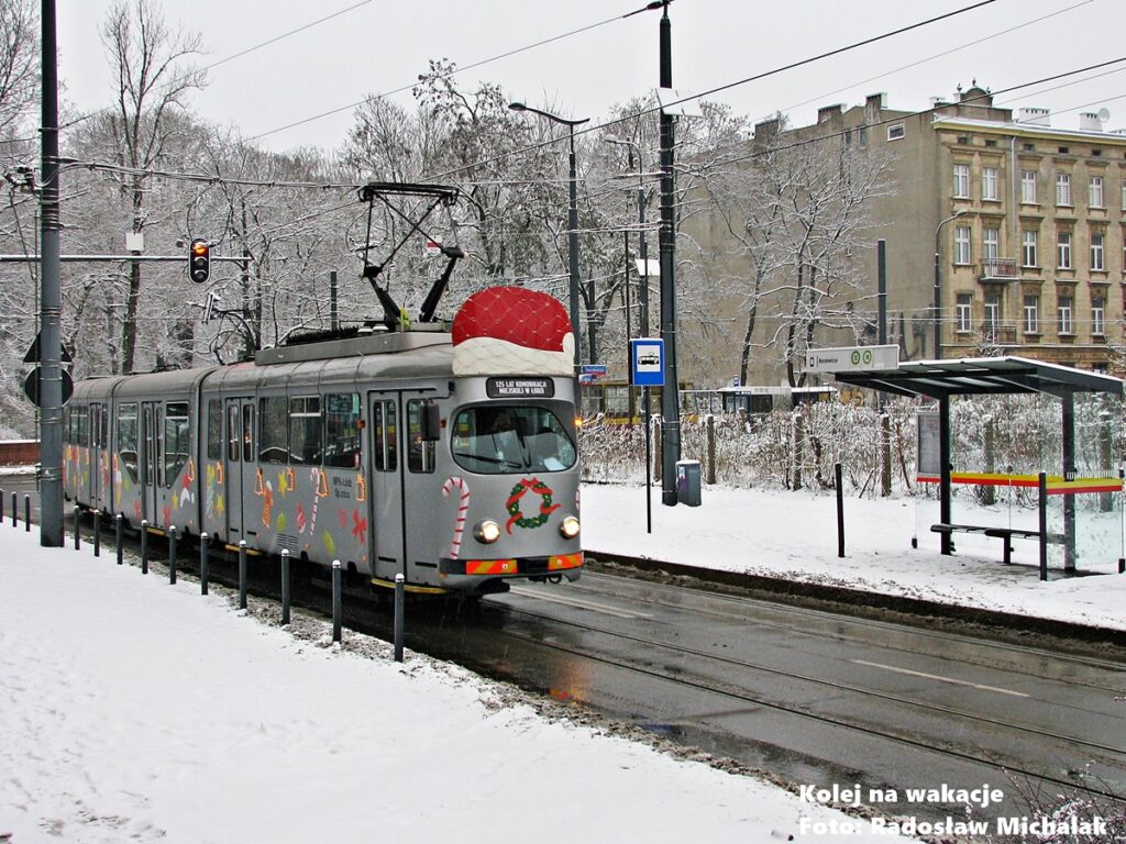 Zabytkowy, imprezowy tramwaj typu GT8 MPK Łódź w czapce św. Mikołaja, jadący zimą po torach na ulicy Tramwajowej.