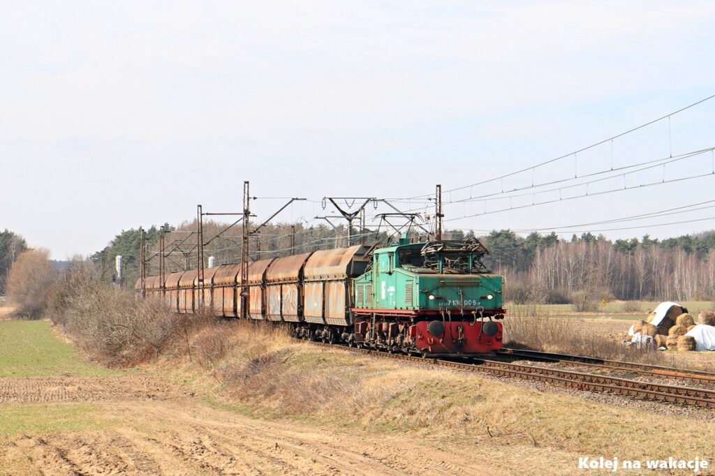 Pociąg górniczy KWB Konin z lokomotywą EL2 (Krokodyl) zbliża się do przejazdu drogowego w Wielkopolsce.