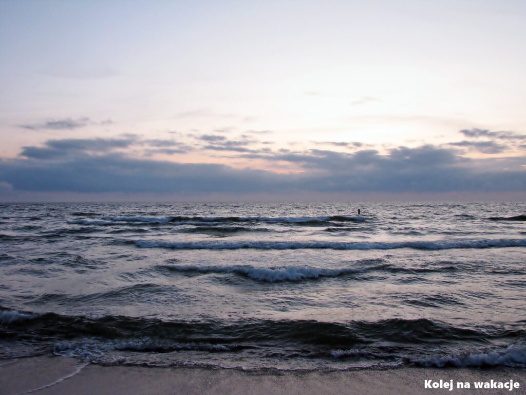 Plaża w Rowach o zachodzie słońca, z zachmurzonym niebem nad Morzem Bałtyckim.