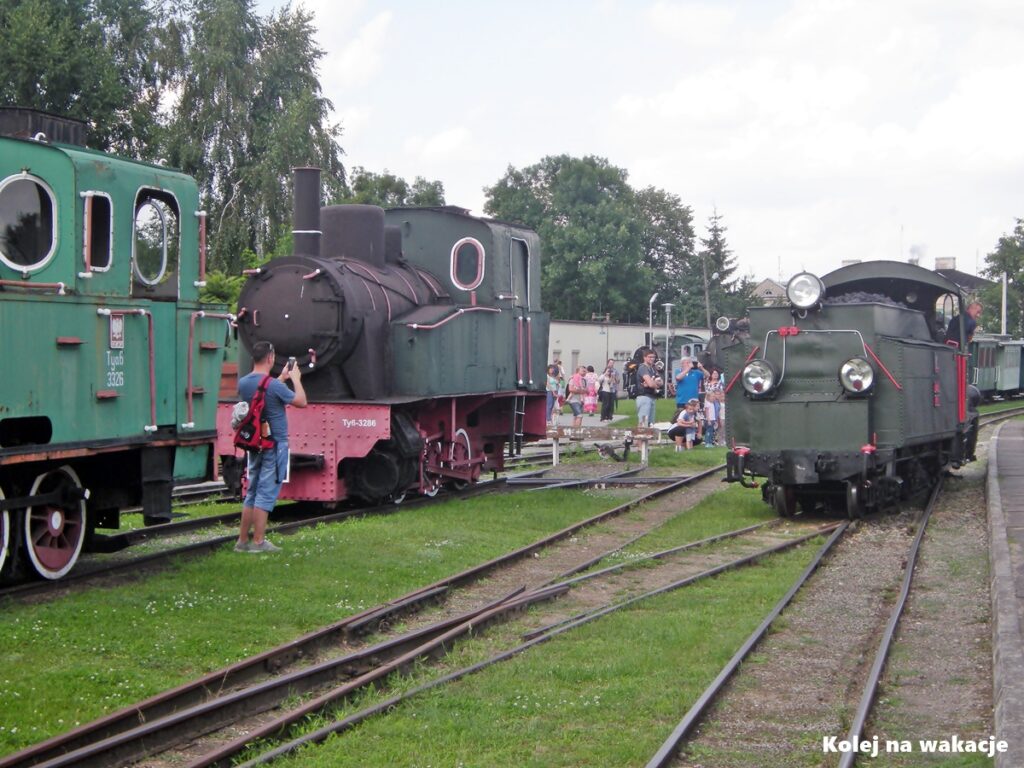 Parowóz wąskotorowy Px29-1704 manewrujący na stacji Muzeum Kolei Wąskotorowej w Sochaczewie w otoczeniu zabytkowego taboru i zwiedzających rodzin z dziećmi.