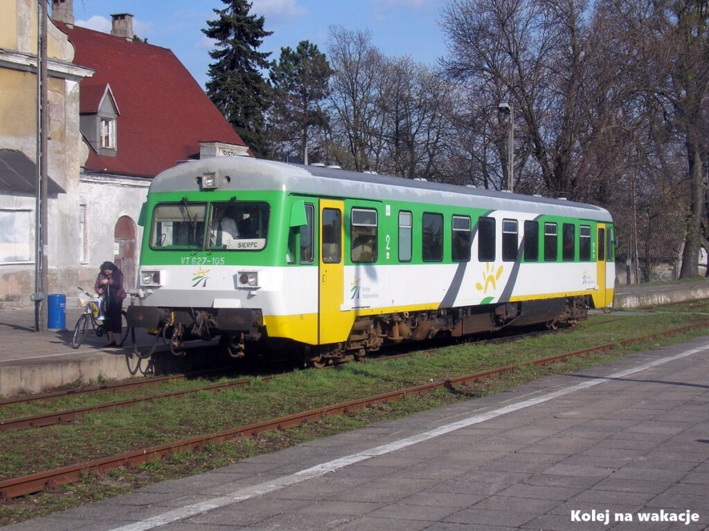 Spalinowy szynobus VT627-105 Kolei Mazowieckich na tle zabytkowego budynku stacji w Sierpcu.