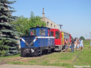Niebieska lokomotywa spalinowa Lyd1-255 z pociągiem turystycznym i pasażerami na stacji Pleszew Kowalew.