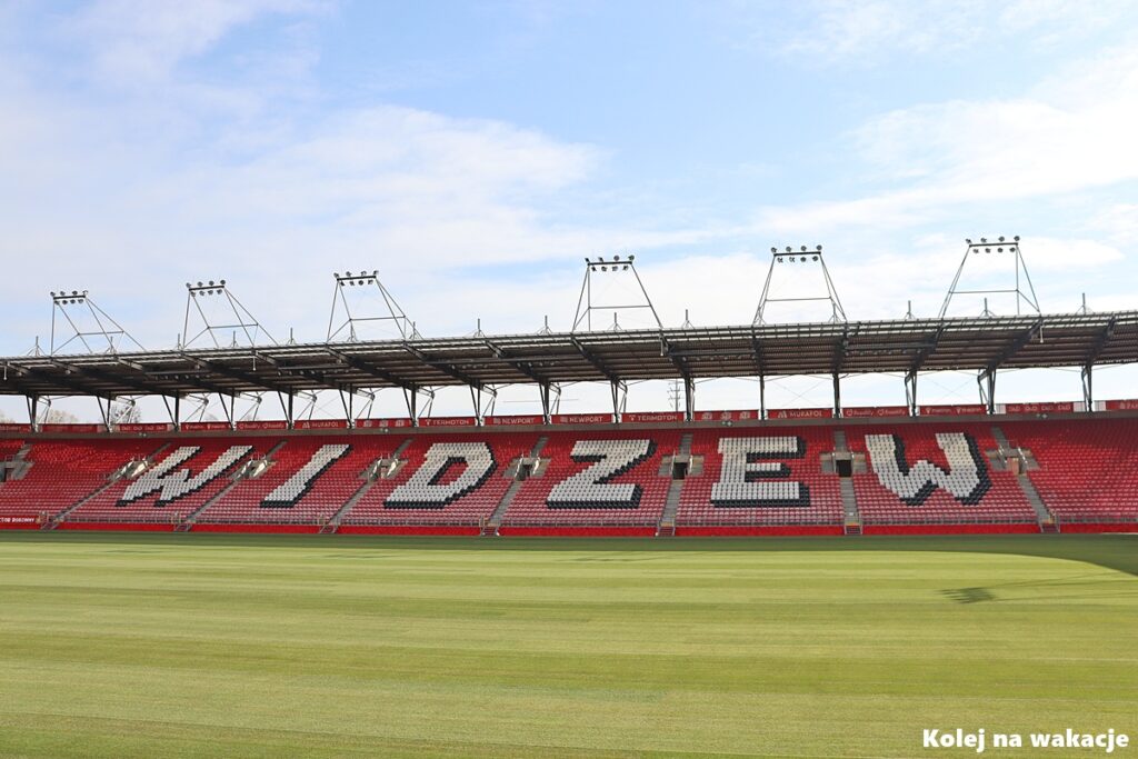 🚋 Jak zwiedzić Łódź tramwajem? Gotowy plan wycieczki po mieście 6 Trybuna stadionu Widzewa Łódź (Serce Łodzi) z białym napisem WIDZEW ułożonym z krzesełek.