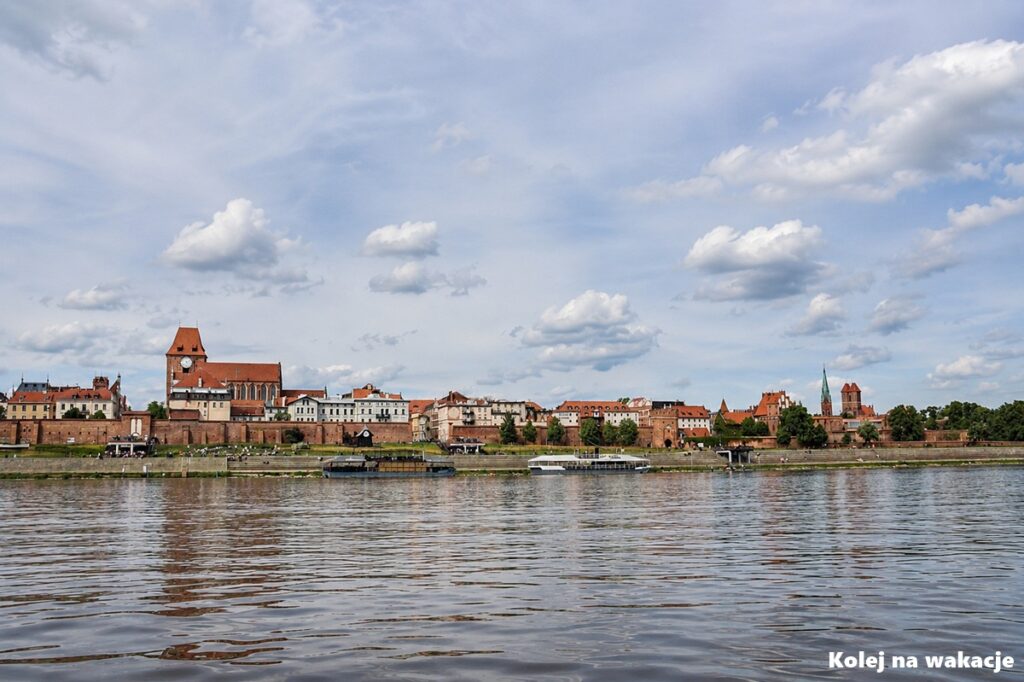 Toruń – sprawdzony plan na weekendową wycieczkę (co zobaczyć + dojazd pociągiem) 1 Panorama toruńskiej Starówki widziana z poziomu rzeki Wisły, sfotografowana z pokładu tradycyjnej łodzi flisackiej.
