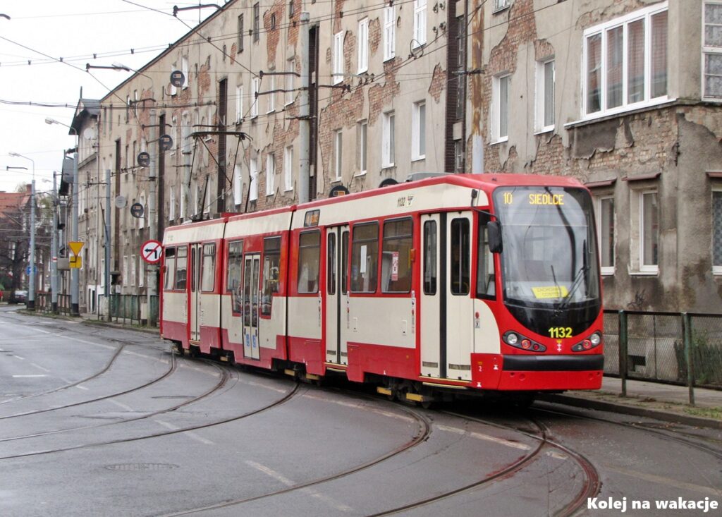 Kremowo-czerwony zmodernizowany tramwaj typu Dortmund na tle historycznych kamienic w Nowym Porcie.