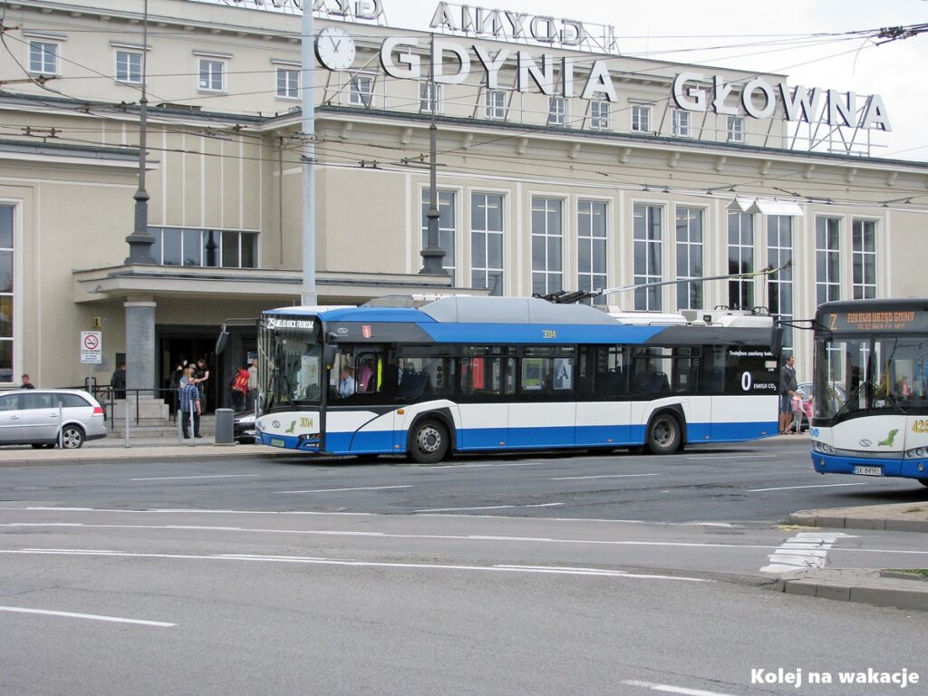 Nowoczesny trolejbus marki Solaris (numer taborowy 3014) posiadający zasilanie bateryjne, stojący na przystanku przed dworcem Gdynia Główna. W tle widoczny fragment starszego pojazdu (nr 4251).