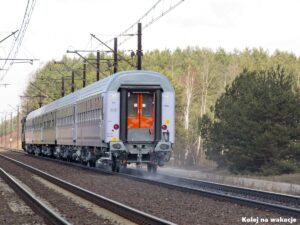 Tył pociągu pasażerskiego PKP Intercity jadącego po torach Centralnej Magistrali Kolejowej (CMK) w okolicach Opoczna na tle lasu.